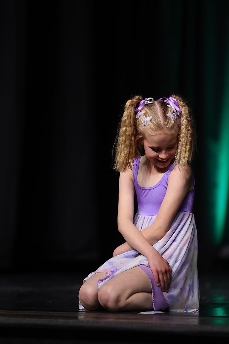 A child in a ballet costume on stage under a spotlight