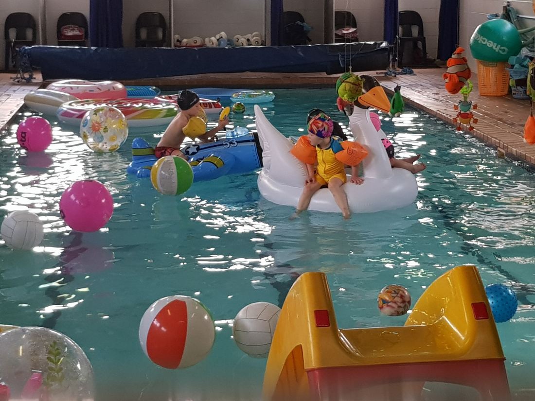 Children playing in a pool filled with beach balls and inflatables at a fun day